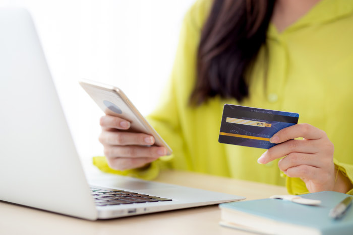 woman-holding-phone-and-debit-card-with-laptop